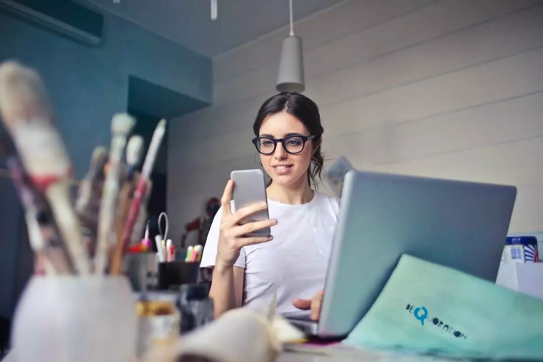 Woman using smartphone at creative workspace.