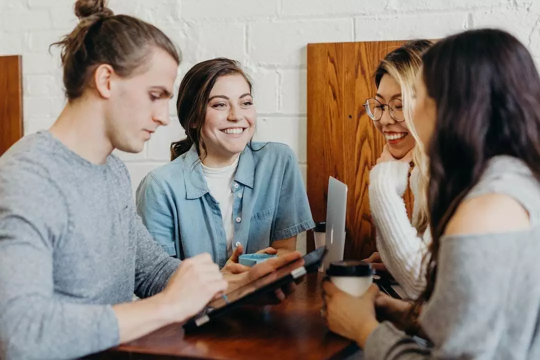 Group of young adults enjoying a conversation at a cafe table.