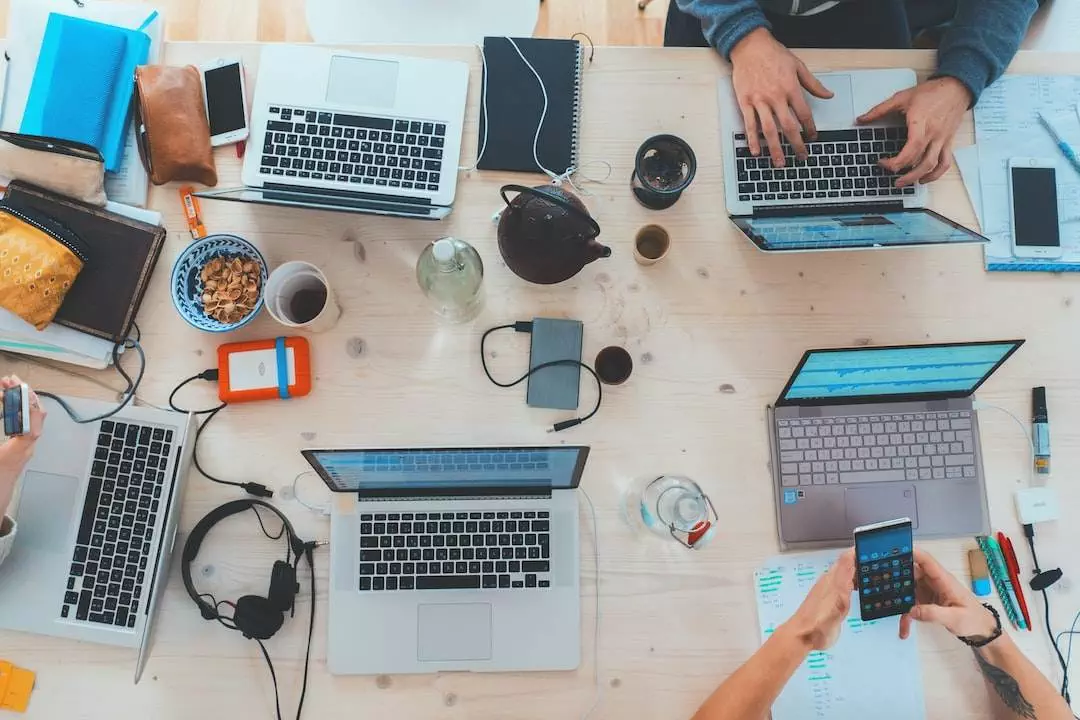 Coworkers at a busy tech office desk.