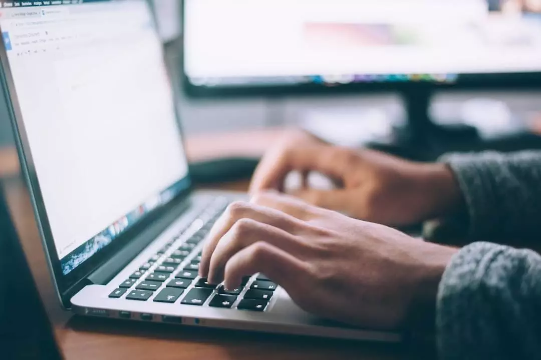 Person typing on laptop keyboard.