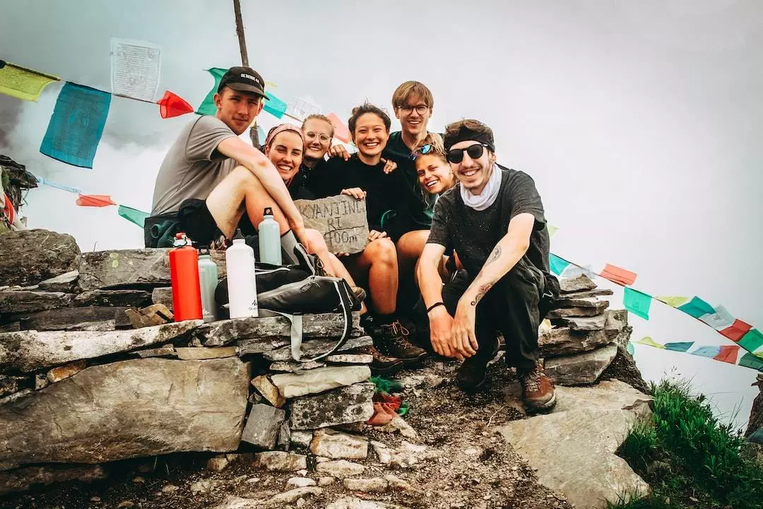 Group of hikers at summit with prayer flags.