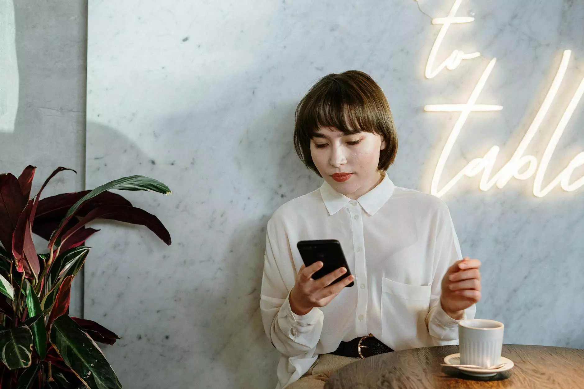 woman in white long sleeve shirt holding black smartphone