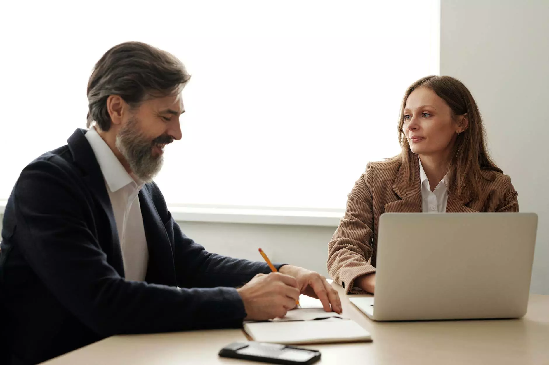 man and woman sitting at the table with a laptop in an office