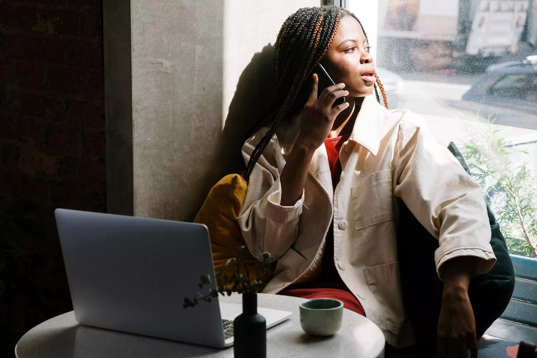 woman in beige coat sitting by the table with macbook