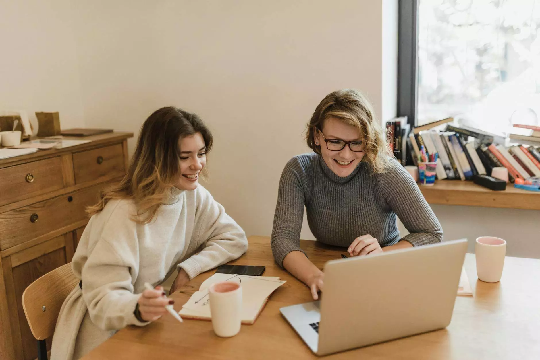 smiling women sitting at desk in office working on laptop