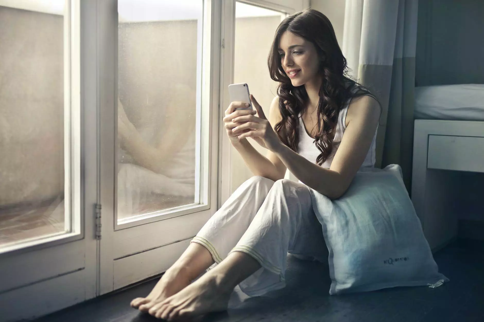 woman sitting beside window holding phone