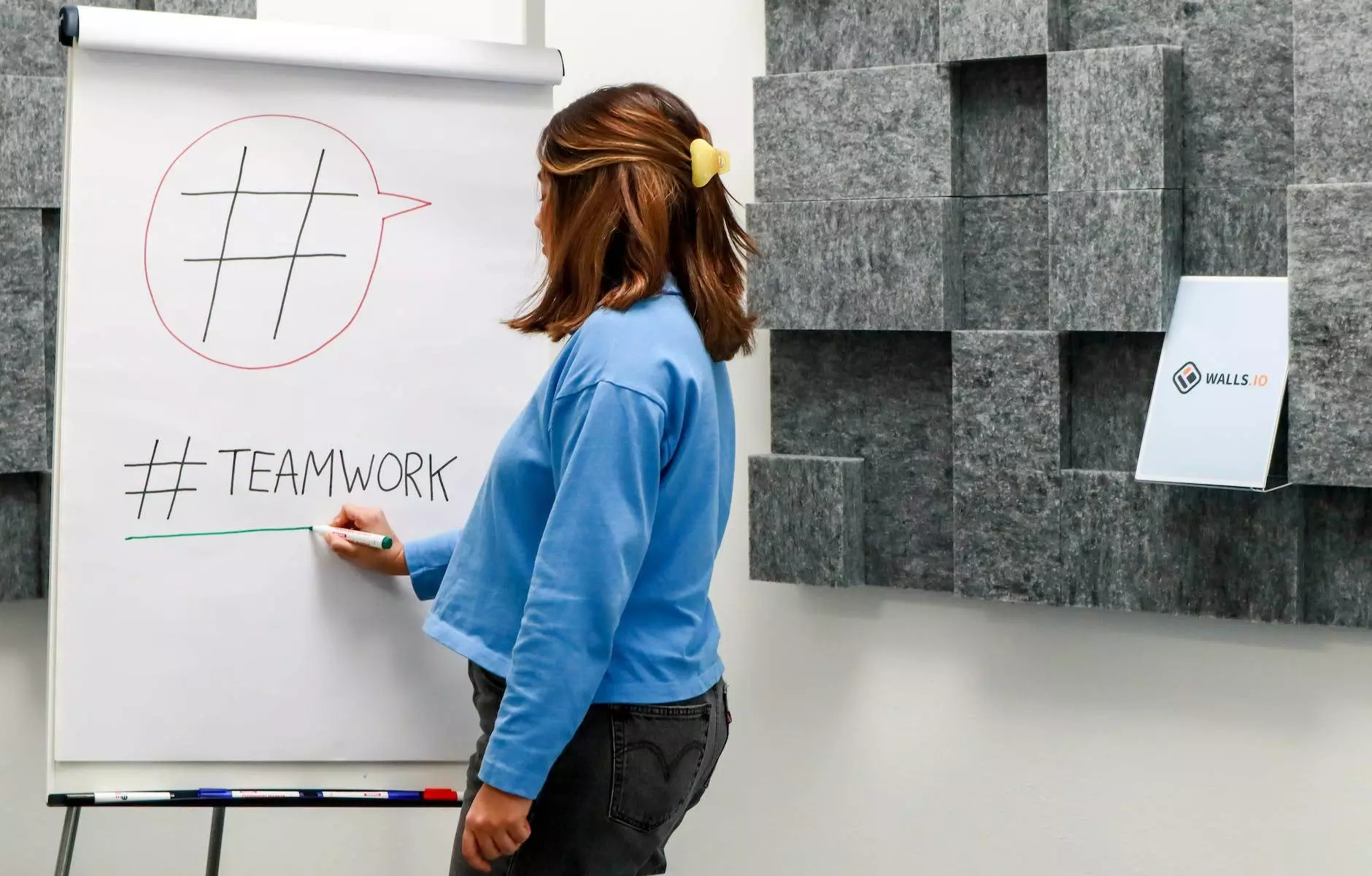 woman in jean jacket writing on board with marker