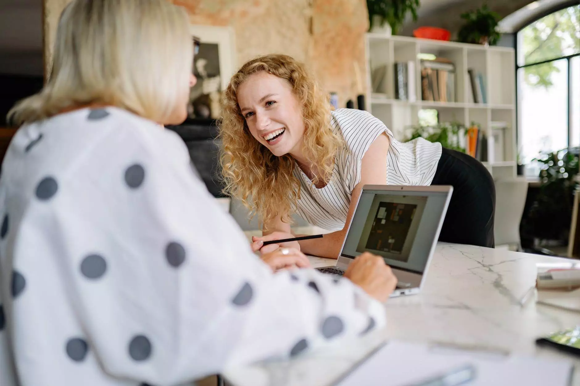 laughing woman leaning on a table talking to her coworker