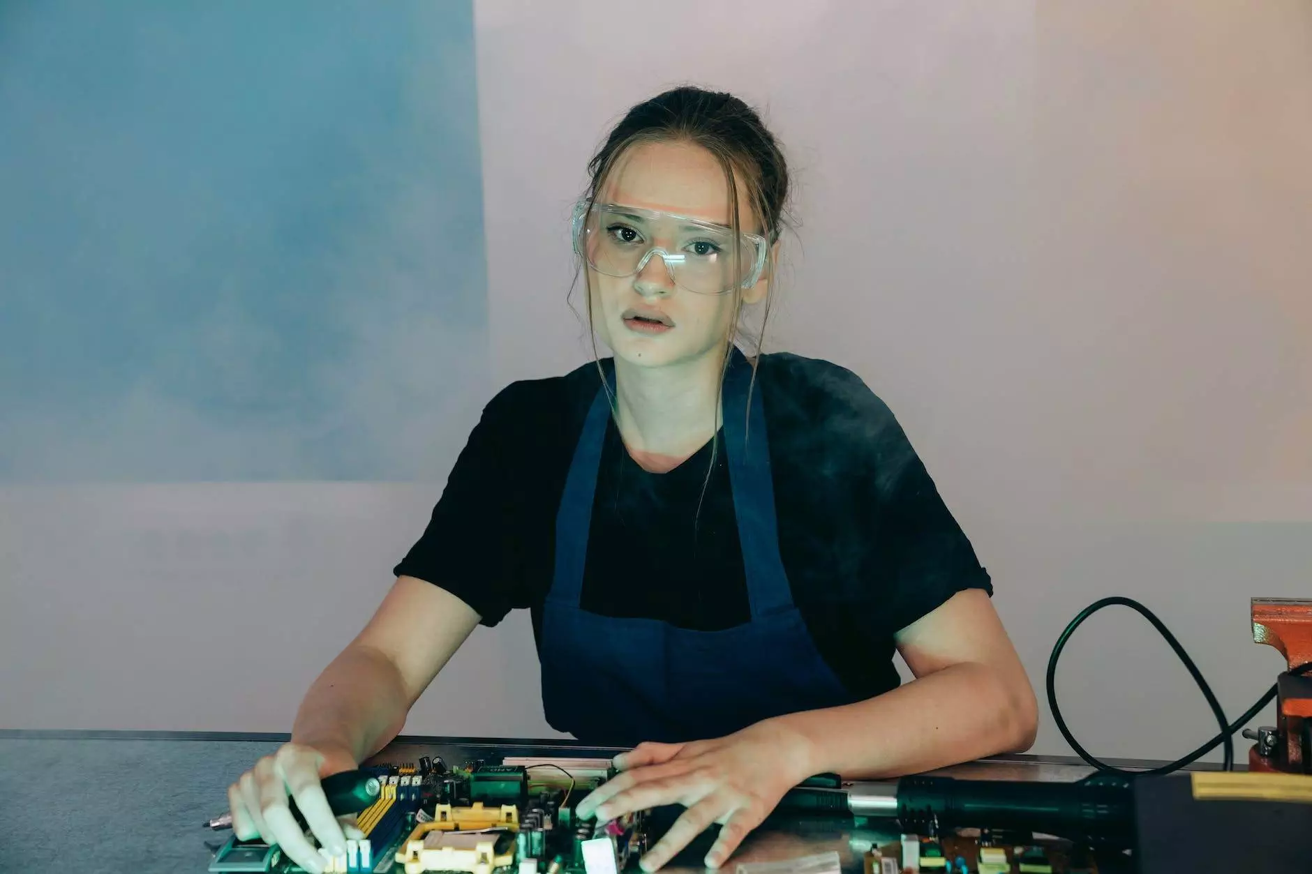 woman in goggles sitting over table with computer hardware