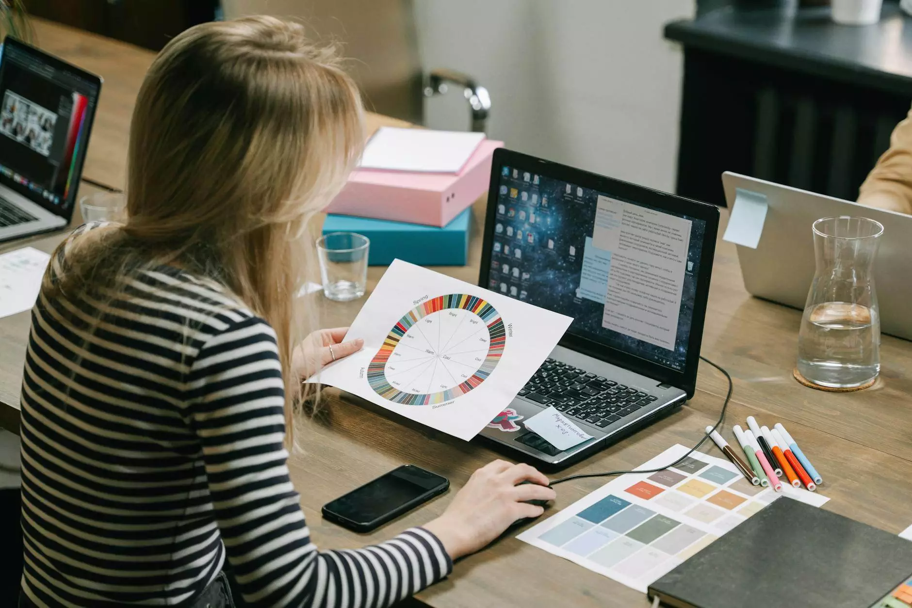 woman looking at a color wheel while using a laptop