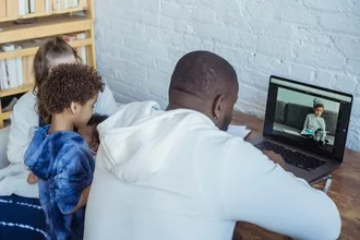 black father working on laptop near kids and mother