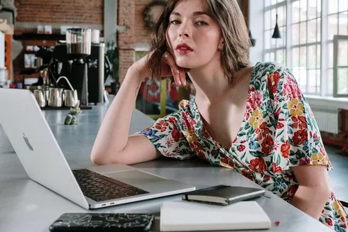 woman in white red and blue floral sleeveless shirt sitting at the table using macbook